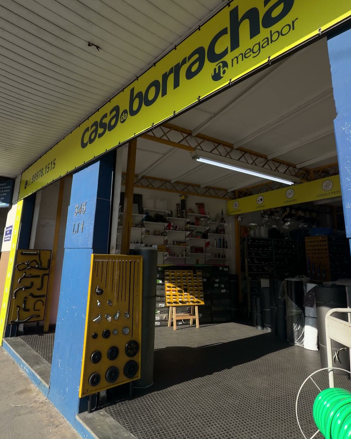 Entrada da Casa da Borracha em Olaria, Nova Friburgo, com painéis de peças, piso de borracha e prateleiras de estoque
